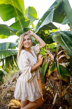 Woman near large green leaf of banana tree on nature in park. Tropical plants