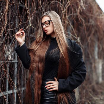 Young beautiful fashionable woman with long hair, in eyeglasses. Female fashion, beauty concept. Outdoor.