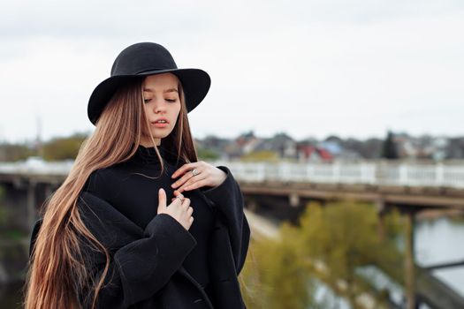 Young beautiful fashionable woman in black hat, with long hair. Female fashion, beauty concept. Outdoor.