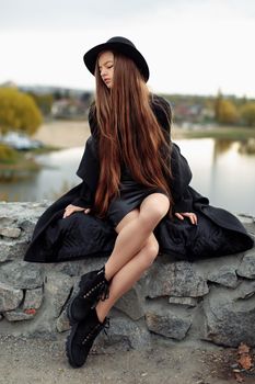 Young beautiful fashionable woman in black hat, with long hair. Female fashion, beauty concept. Outdoor.