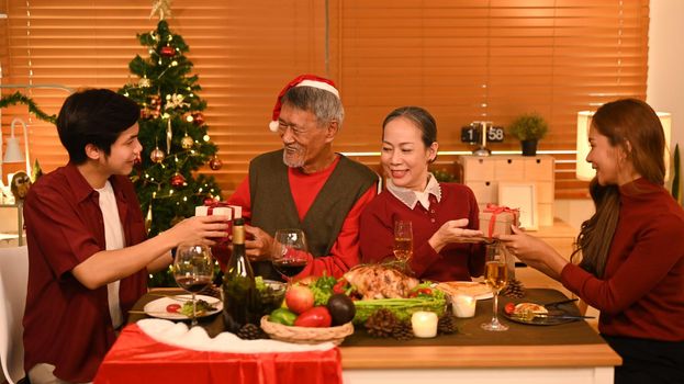 Image of happy family celebrating Christmas together at home lighted with soft lights and candles. Celebration, holidays and people concept.