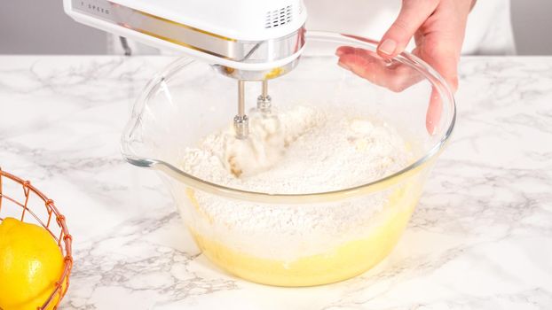 Step by step. Mixing ingredients in a glass mixing bowl to prepare lemon bundt cake.