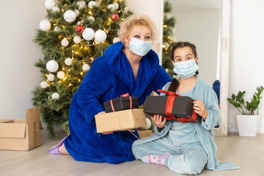 Grandmother with grandchild in a protective masks. Waiting for Christmas. Quarantin, isolated. Coronavirus covid-19. Family leisure.