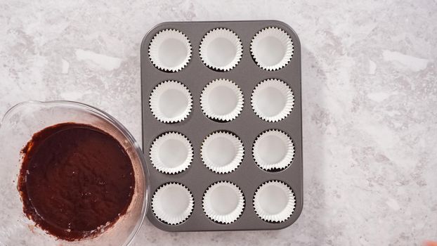 Flat lay. Step by step. Scooping chocolate cupcake dough into the cupcake liners.