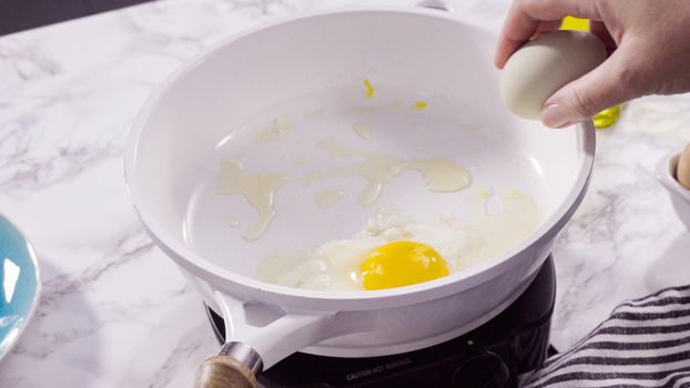 Frying farm fresh eggs in a white skillet.