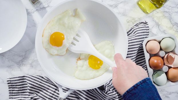 Flat lay. Frying farm fresh eggs in a white skillet.