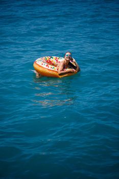 Carefree young girl woman enjoying a relaxing day at sea, floating on an inflatable ring, top view. Sea vacation concept