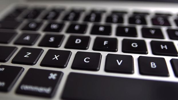 Close-up macro panoramic view of keyboard on the laptop computer. Slow macro soft focus dolly shot. 4k footage of modern laptop keyboard