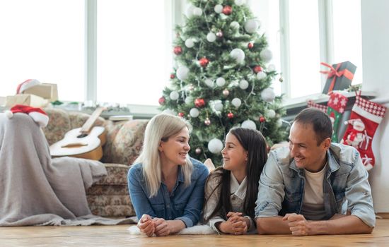 happy family mother, father and child daughter near Christmas tree at home.