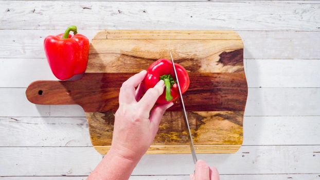 Flat lay. Mincing organic red bell peppers on a wood cutting board.