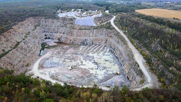 Aerial drone view of career in Europe at summer sunset, crushed stone quarry, beautiful nature round, some excavators, diggers inside