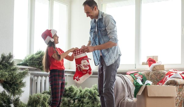 Father and daughter assembling christmas tree, smiling - christmas, holiday, winter concept, family activity