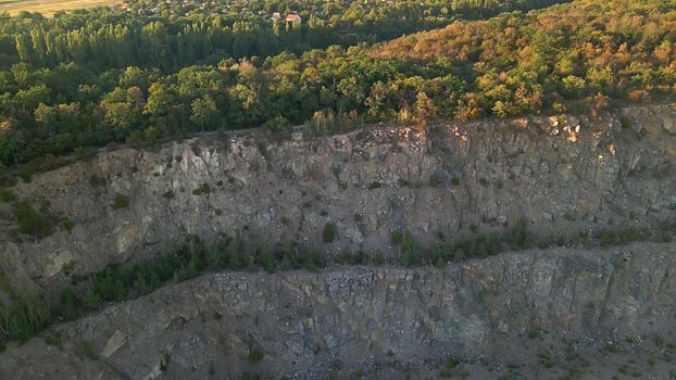 Aerial drone view of career in Europe at summer sunset, crushed stone quarry, beautiful nature round, some excavators, diggers inside