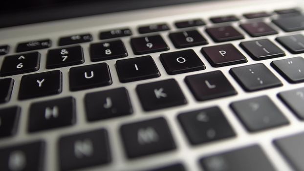 Close-up macro panoramic view of keyboard on the laptop computer. Slow macro soft focus dolly shot. 4k footage of modern laptop keyboard