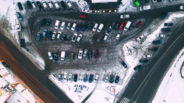 Aerial top down view of small supermarket parking lot with cars at winter evening. Time lapse, 4k footage