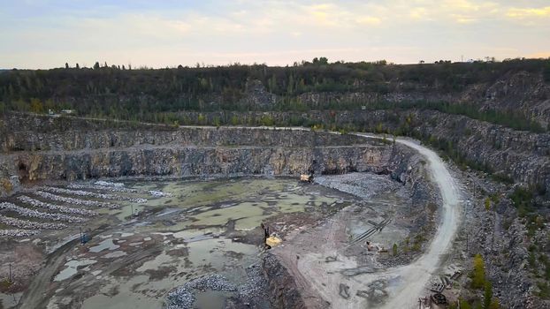 Aerial drone view of career in Europe at summer sunset, crushed stone quarry, beautiful nature round, some excavators, diggers inside