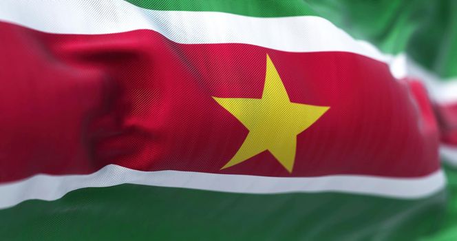 Close-up view of Suriname national flag waving in the wind. The Republic of Suriname is a country on the northeastern Atlantic coast of South America. Fabric textured background. Selective focus