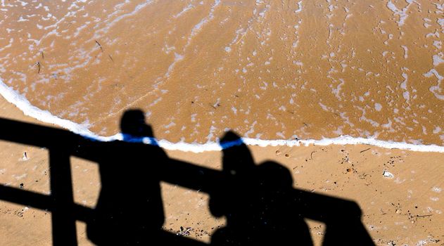 Arenales del Sol, Alicante, Spain- September 18, 2022: People silhouettes by the shore on the beach on a Sunny day of Summer