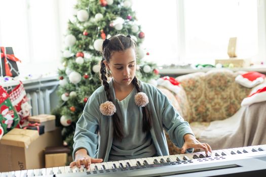 Christmas child little girl playing on piano at home.