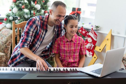 father and daughter playing the piano at christmas.