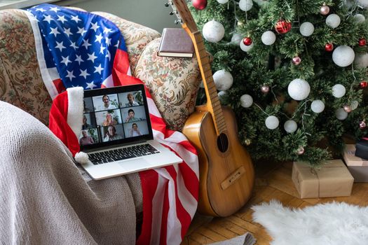 Online party with loved ones from USA. Celebrating Christmas video chat. Virtual party via video messenger. Americans new year are video chatting. New Year gifts and flag of America next to computer.