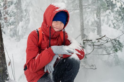 Portrait of teenage boy walking and having fun in winter snowing forest