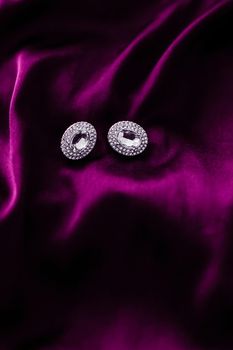 Jewellery brand, elegant fashion and bridal luxe gift concept - Luxury diamond earrings on dark pink silk fabric, holiday glamour jewelery present