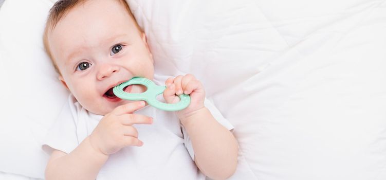 A baby with a teether on a white background . Teething. Children's article. Copy space