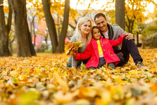 A Family enjoying golden leaves in autumn park.