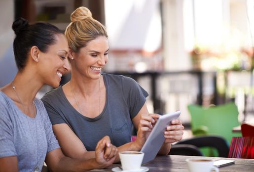 Technology brings people closer. Two young women looking at a tablet in a coffee shop