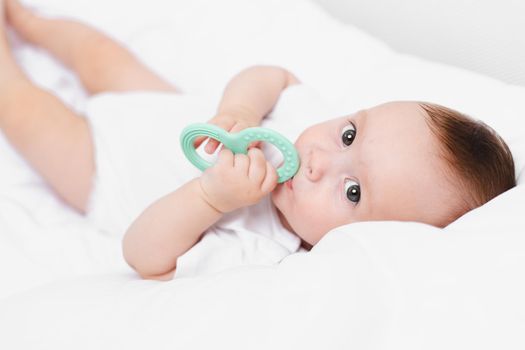 A baby with a teether on a white background . Teething. Children's article. Copy space