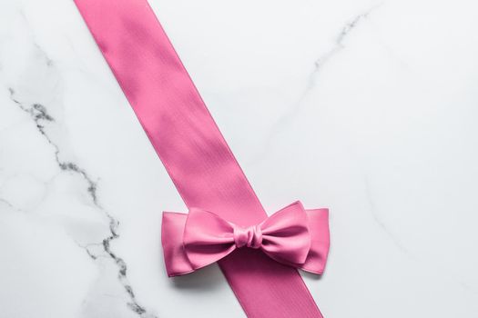 Birthday, wedding and girly branding concept - Pink silk ribbon and bow on marble background, girl baby shower present and glamour fashion gift decor for luxury beauty brand, holiday flatlay design