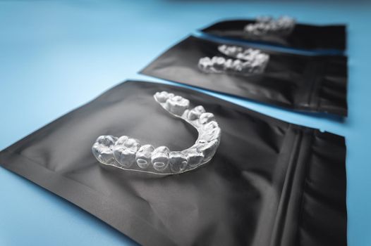 new transparent plastic braces lie on a special orthodontic package with a zipper on a blue background, studio shot, nobody.