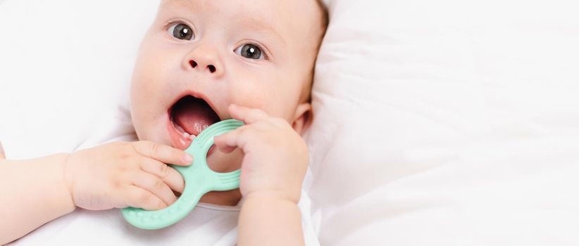 A baby with a teether on a white background . Teething. Children's article. Copy space