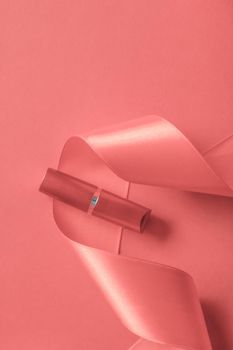 Cosmetic branding, glamour lip gloss and shopping sale concept - Luxury lipstick and silk ribbon on coral holiday background, make-up and cosmetics flatlay for beauty brand product design