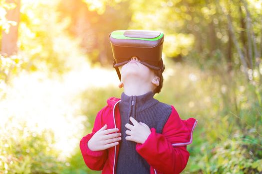 A boy in virtual reality glasses on the street . Modern children . 3D glasses. Modern technologies. Virtual games