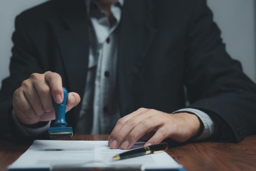 Man stamping approval of work finance banking or investment marketing documents on desk.