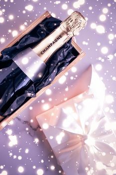 Celebration, drink and branding concept - Champagne bottle and gift box on purple holiday glitter, New Years, Christmas, Valentines Day, winter present and luxury product packaging for beverage brand