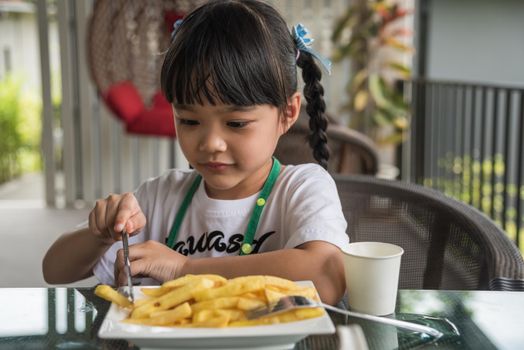 Young Asian girl eating french fries young kid fun happy potato fast food.