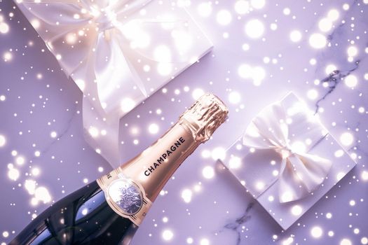 Celebration, drink and branding concept - Champagne bottle and gift box on purple holiday glitter, New Years, Christmas, Valentines Day, winter present and luxury product packaging for beverage brand