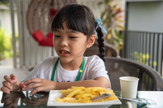 Young Asian girl eating french fries young kid fun happy potato fast food.