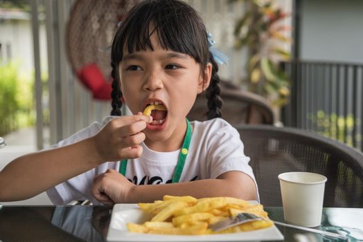 Young Asian girl eating french fries young kid fun happy potato fast food.