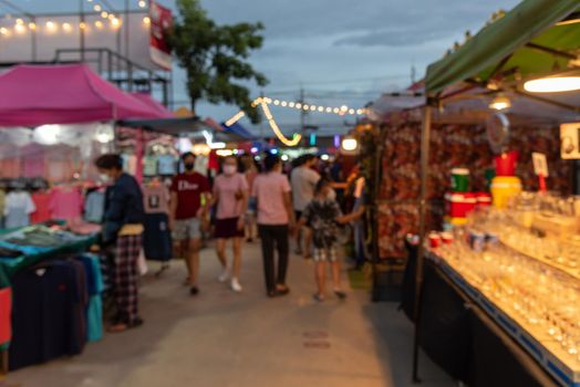 blurred image of night market festival people walking on road with light bokeh for background.