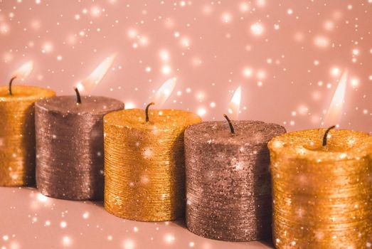 Winter, celebration and new years eve concept - Christmas candles and shiny snow on golden background, holiday season decoration
