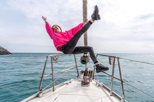 Woman standing on the nose of the yacht at a sunny summer day, breeze developing hair, beautiful sea on background.