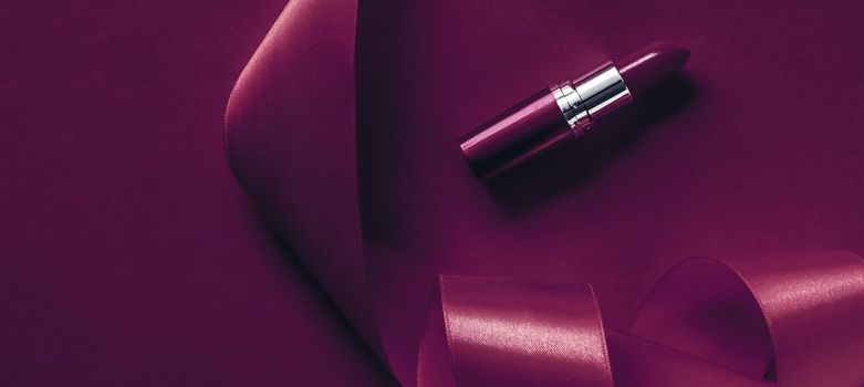 Cosmetic branding, glamour lip gloss and shopping sale concept - Luxury lipstick and silk ribbon on plum holiday background, make-up and cosmetics flatlay for beauty brand product design