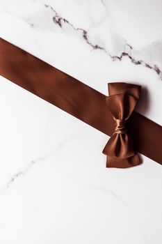 Holiday gift, decoration and sale promotion concept - Chocolate brown silk ribbon on marble background, flatlay