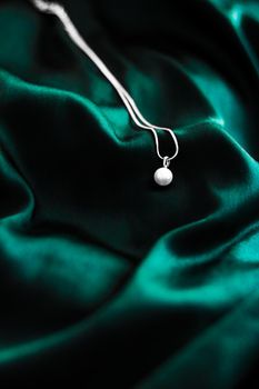 Jewellery brand, elegant fashion and bridal luxe gift concept - Luxury white gold pearl necklace on dark emerald green silk background, holiday glamour jewelery present