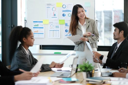 Female Operations Manager Holds Meeting Presentation for a Team of Economists. Asian Woman Uses Digital Whiteboard with Growth Analysis, Charts, Statistics and Data. People Work in Business Office..