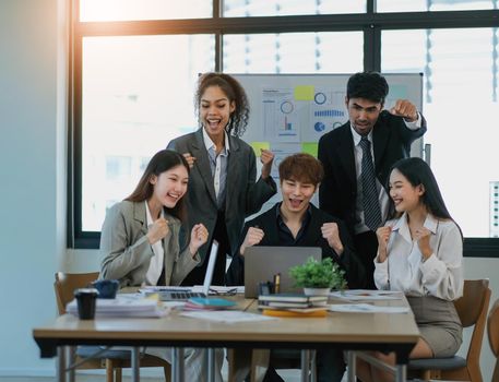 Young happy Asian business man, woman work together, celebrate success in start up office. Creative team brainstorm meeting, businesspeople colleague partnership or office coworker teamwork concept.